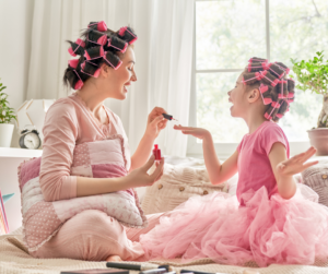 Mother and daughter in curlers and pink outfits sharing a fun pampering moment together