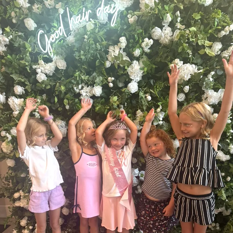 Five girls celebrating a Lil Glam birthday party in front of the flower wall at The Ready Room