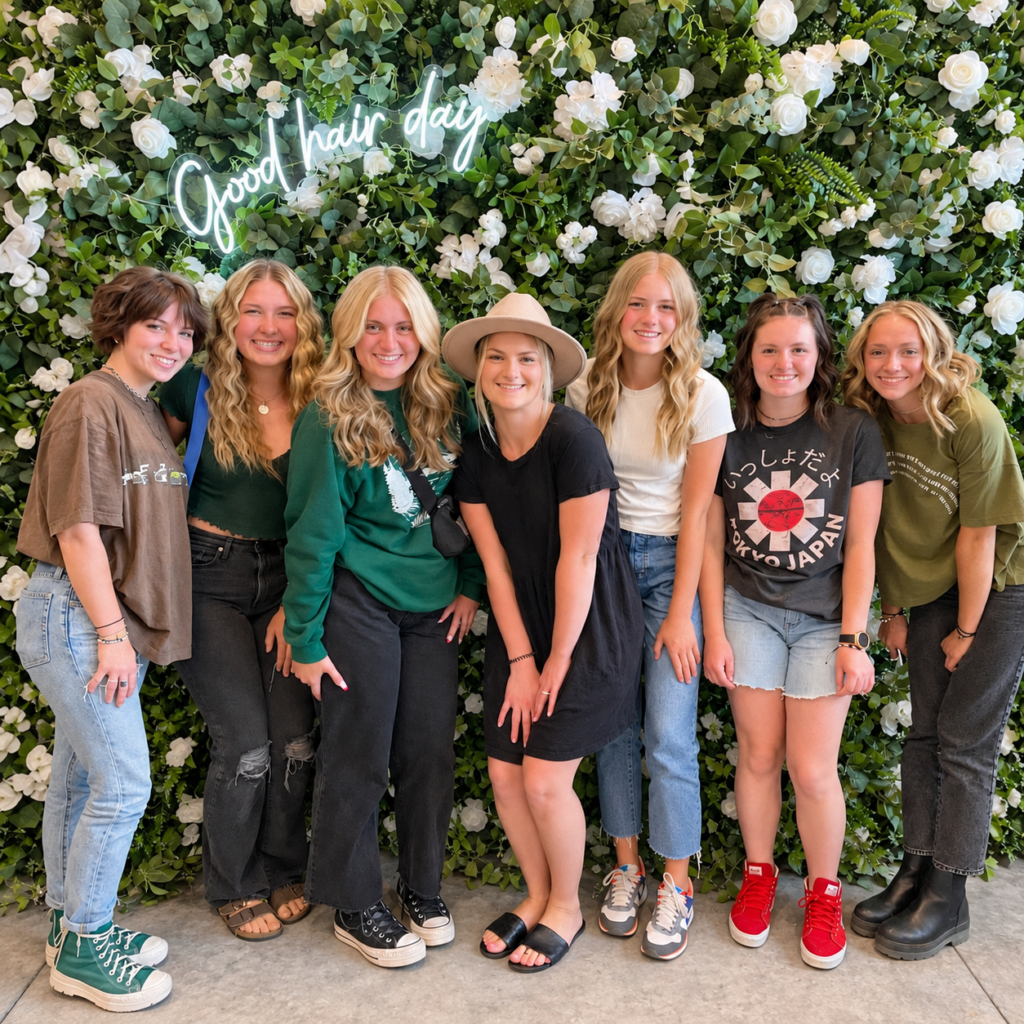 Seven friends posing in front of the flower wall at a Teen Glam party at The Ready Room
