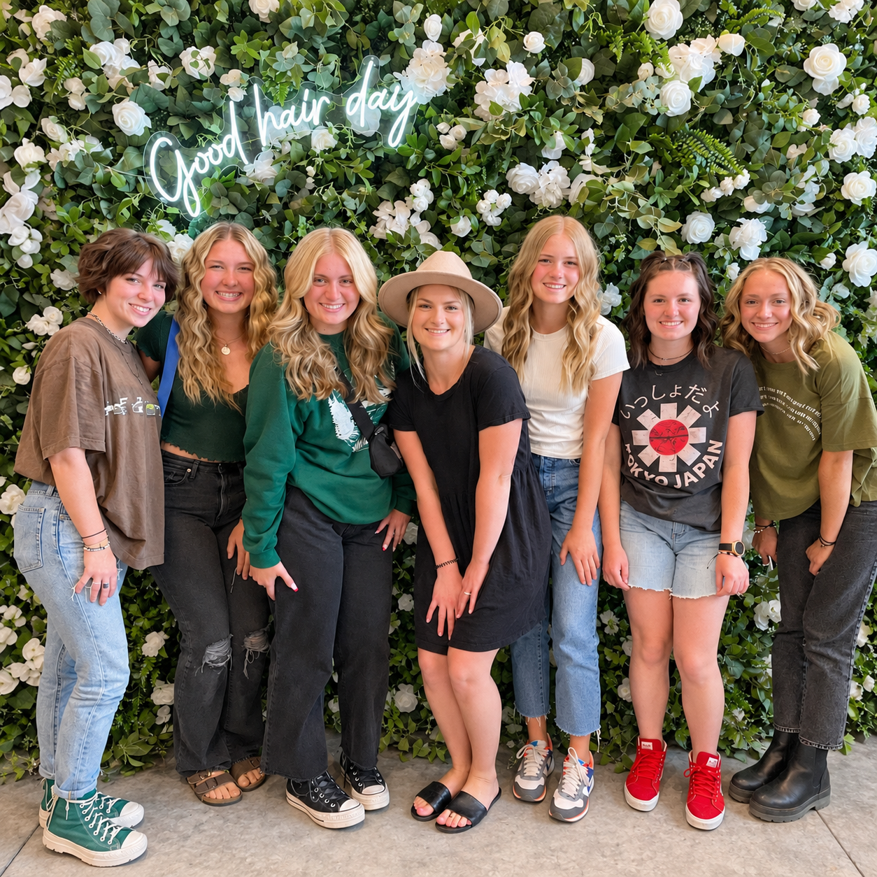 Seven friends posing in front of the flower wall at a Teen Glam party at The Ready Room